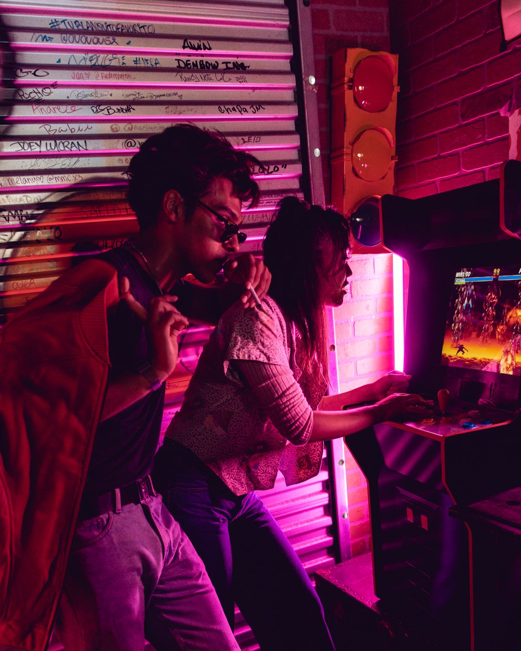 Dos personas sentadas frente a frente jugando videojuegos en arcade