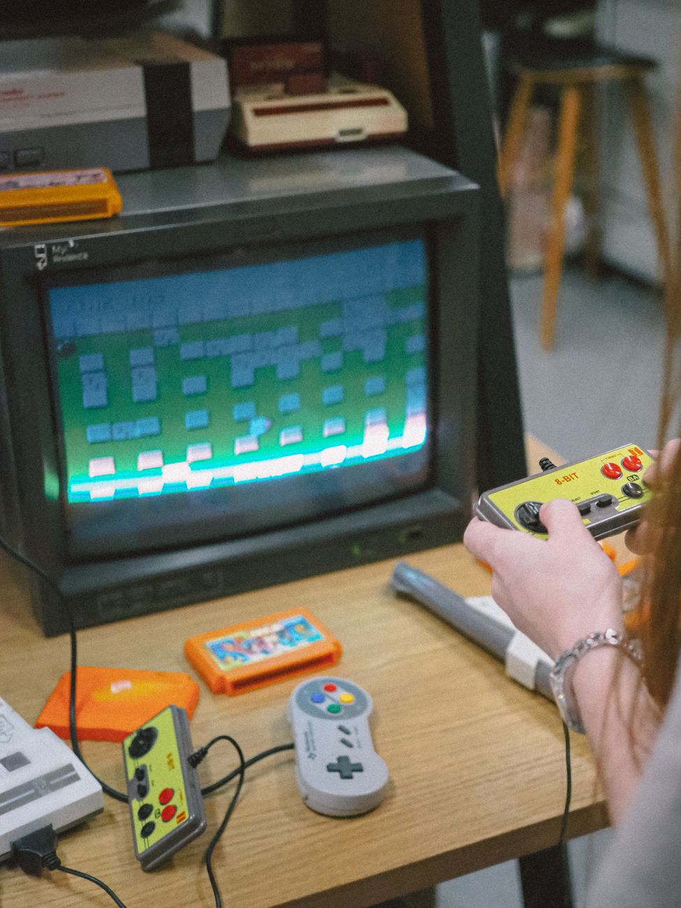 Jugador utilizando un joystick frente a una pantalla de televisión retro con un juego clásico